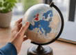 Hand houdt wereldbol vast met focus op Europa en het Verenigd Koninkrijk als symbool voor internationale handel en de impact van de Brexit.