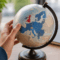 Hand houdt wereldbol vast met focus op Europa en het Verenigd Koninkrijk als symbool voor internationale handel en de impact van de Brexit.